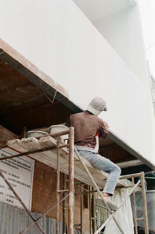 Pekerja konstruksi mengecat bangunan saat renovasi rumah di Indonesia